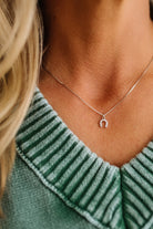 Silver necklace with a horseshoe-shaped pendant on a light gray background