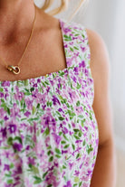 Person wearing a floral dress with a gold necklace