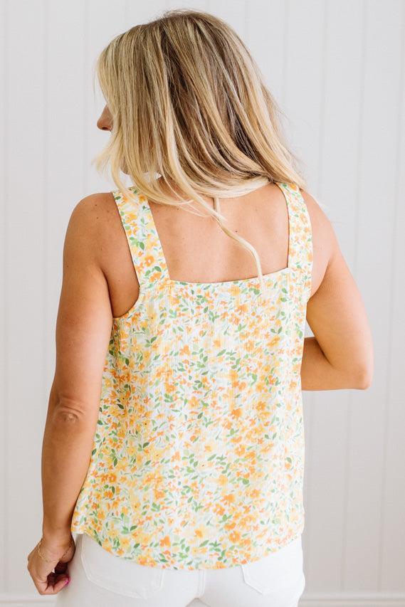 Woman wearing a floral sleeveless top against a white background