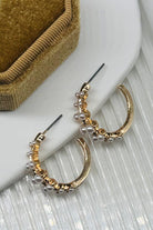 Gold and pearl hoop earrings on a white surface with a brown fabric background