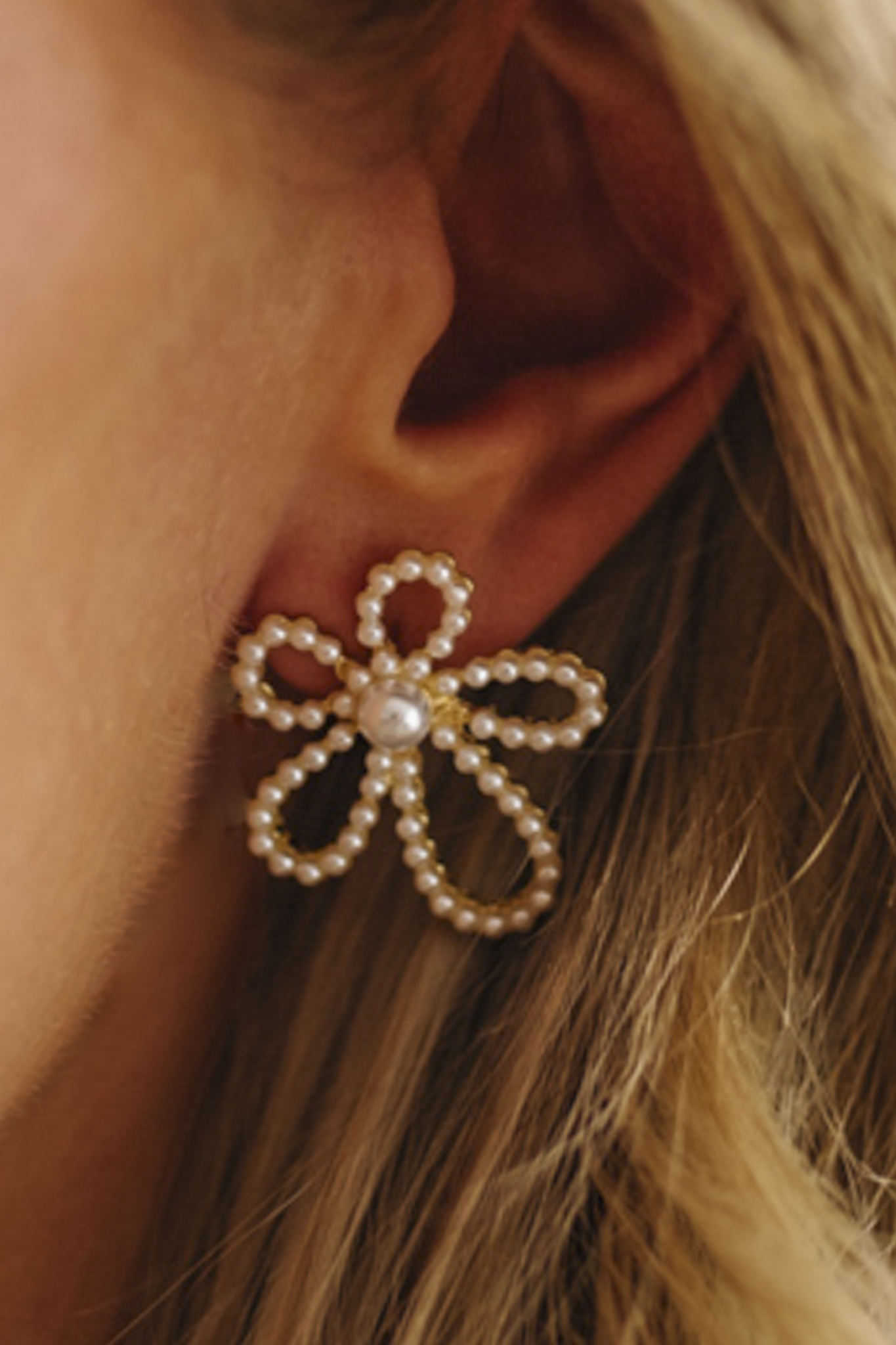Close-up of a person wearing a decorative earring with pearls.