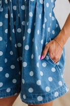 Close-up of a blue romper with white polka dots worn by a person.
