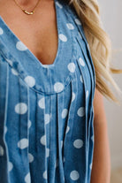 Blue romper with white polka dots worn by a person with a neutral background