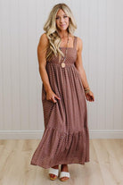 Woman wearing a patterned dress standing against a white wall.