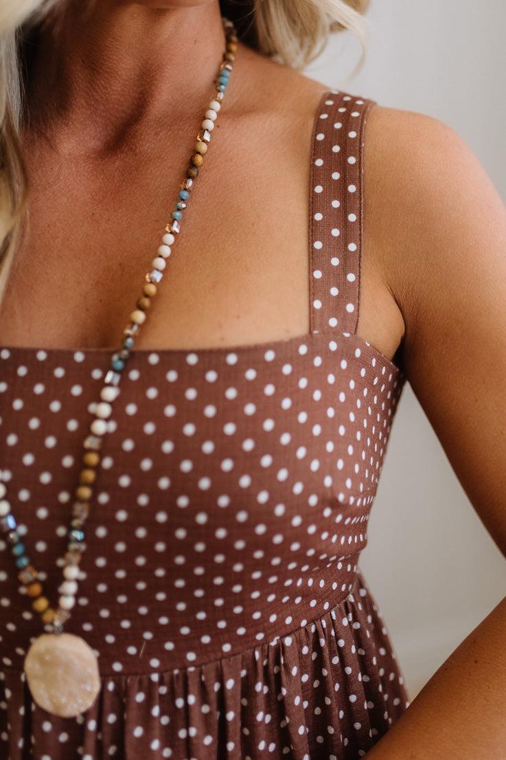 Brown polka dot dress with a necklace worn by a person