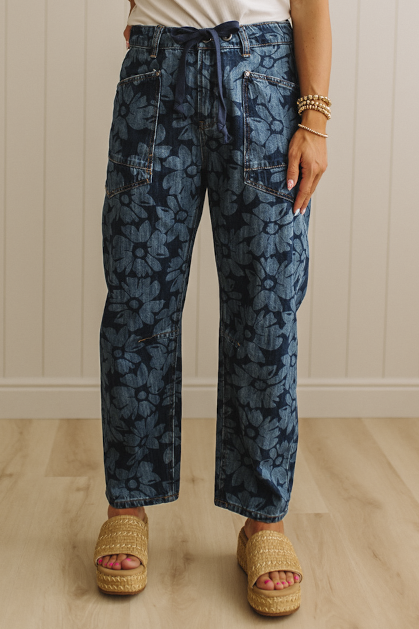 Person wearing blue floral-patterned pants with a white wall background