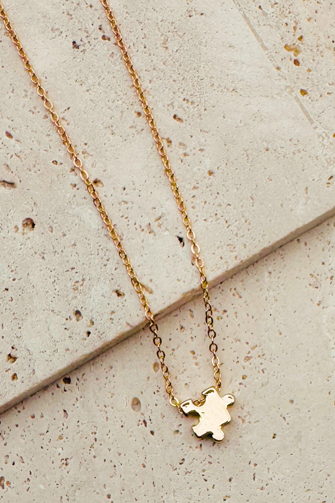 Gold necklace with a small pendant on a textured surface