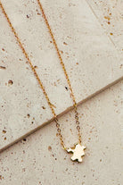 Gold necklace with a small pendant on a textured surface