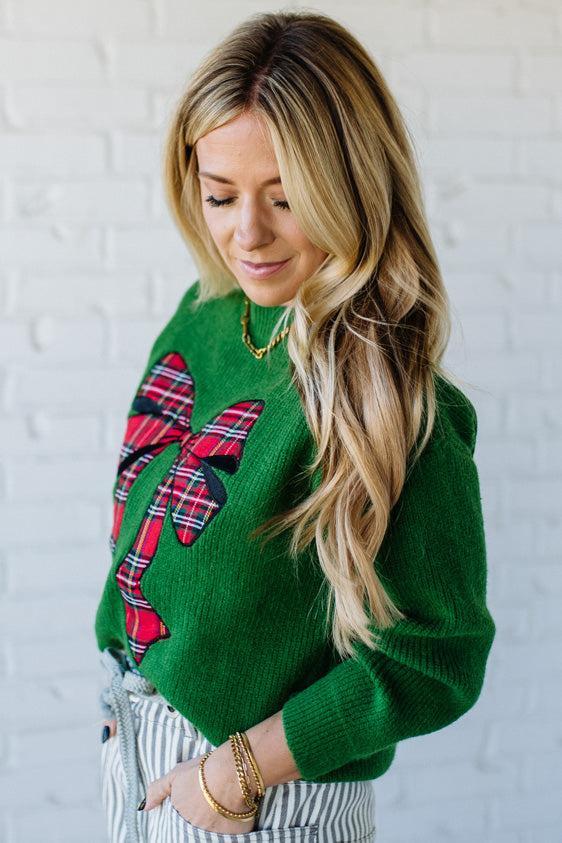 BLONDE WOMAN WEARING CHECKERED PLAID BIG RIBBON CHRISTMAS HOLIDAY LOOSE FIT SWEATER PULL OVER TOP