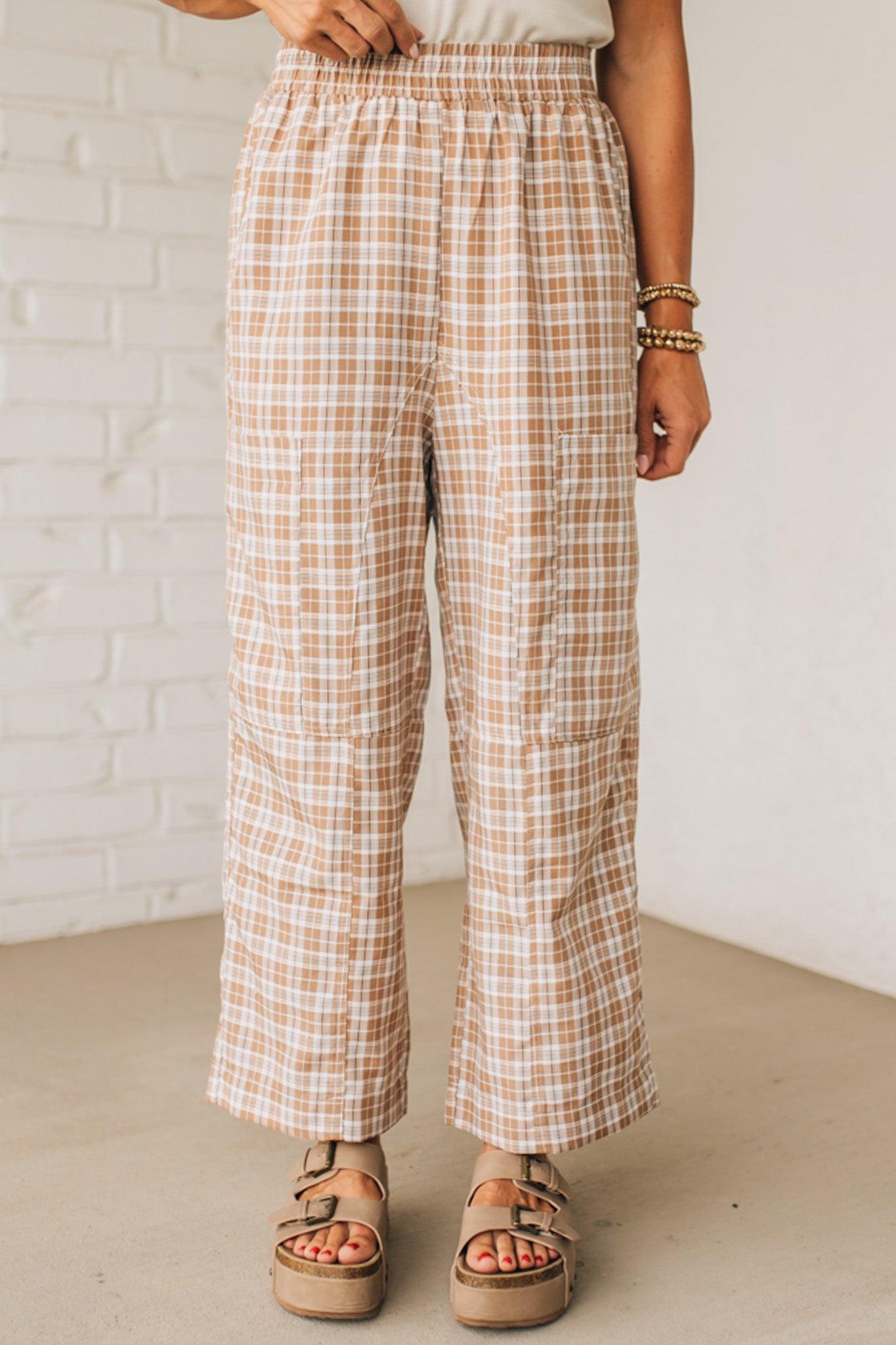 WOMAN WEARING A WHITE TEE AND BROWN SANDALS WITH CHECK PLAID WIDE LEG PANTS WITH THAT HAVE BIG PATCH POCKETS AND ELASTICIZED WAIST.