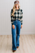 BLONDE WOMAN IN A BROWN HAT WEARING A GREEN CREW NECK, LONG SLEEVE, PLAID PRINTED HACCI TOP