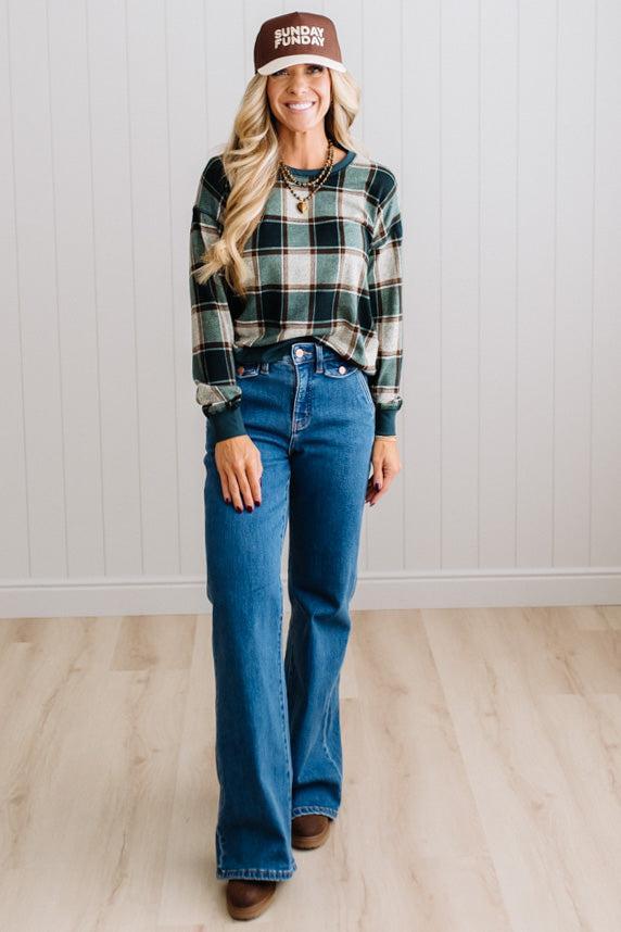 BLONDE WOMAN IN A BROWN HAT WEARING A GREEN CREW NECK, LONG SLEEVE, PLAID PRINTED HACCI TOP