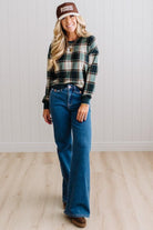 BLONDE WOMAN IN A BROWN HAT WEARING A GREEN CREW NECK, LONG SLEEVE, PLAID PRINTED HACCI TOP