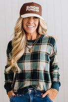 BLONDE WOMAN IN A BROWN HAT WEARING A GREEN CREW NECK, LONG SLEEVE, PLAID PRINTED HACCI TOP