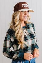 BLONDE WOMAN IN A BROWN HAT WEARING A GREEN CREW NECK, LONG SLEEVE, PLAID PRINTED HACCI TOP