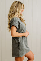 Woman wearing a gray t-shirt dress against a light wooden panel background