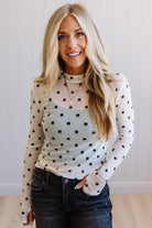 Woman wearing a polka dot top with a plain background