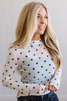 Woman wearing a polka dot blouse with a plain background