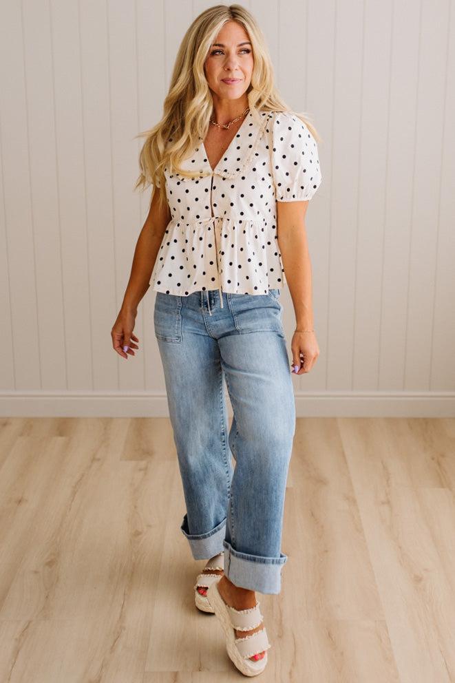 Blonde woman wearing a ivory and black Polka Dot Woven Peter Pan Collar Top with double tie front.