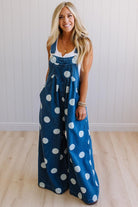 Woman wearing blue denim overalls with white polka dots indoors.