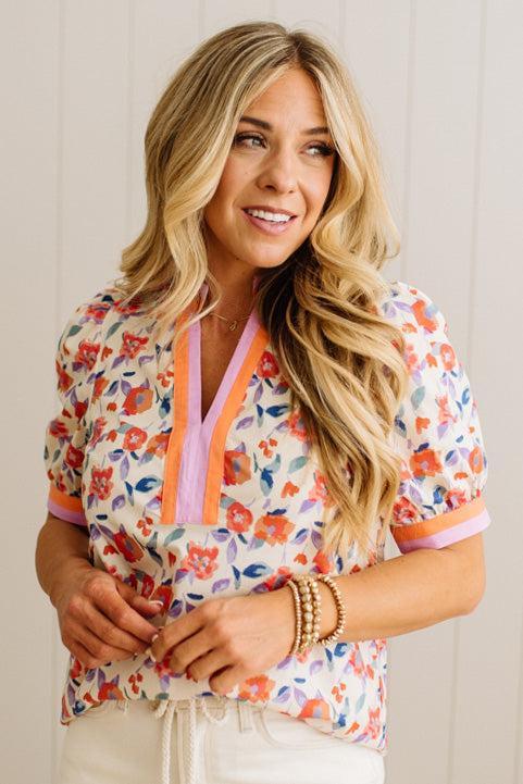 Woman wearing a colorful floral blouse against a plain background