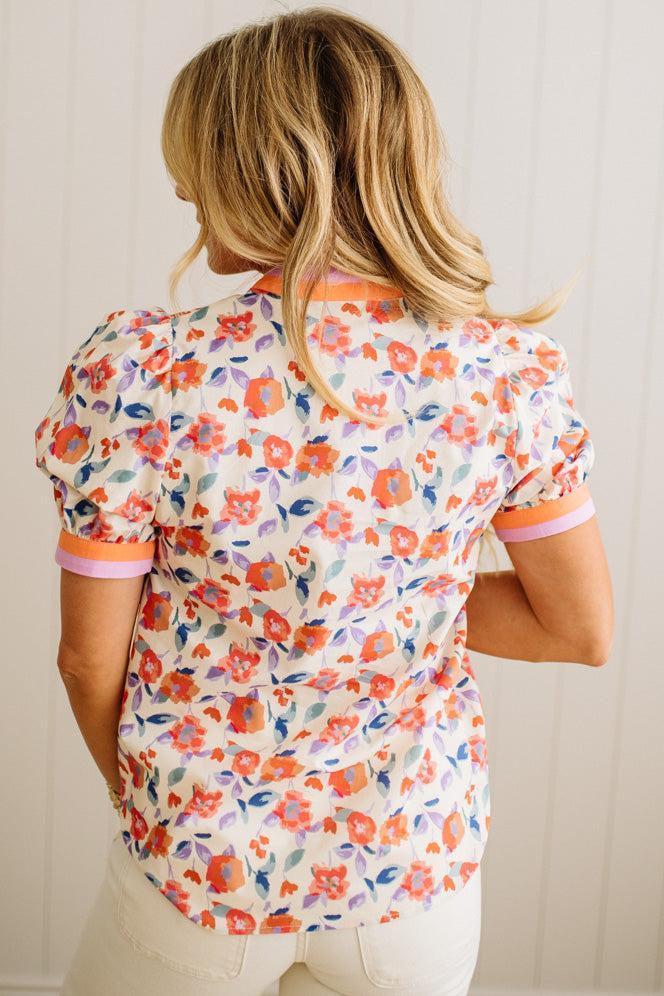 Woman wearing a floral patterned shirt with a neutral background