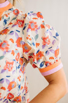 Close-up of a floral-patterned outfit with orange and pink accents on a plain background