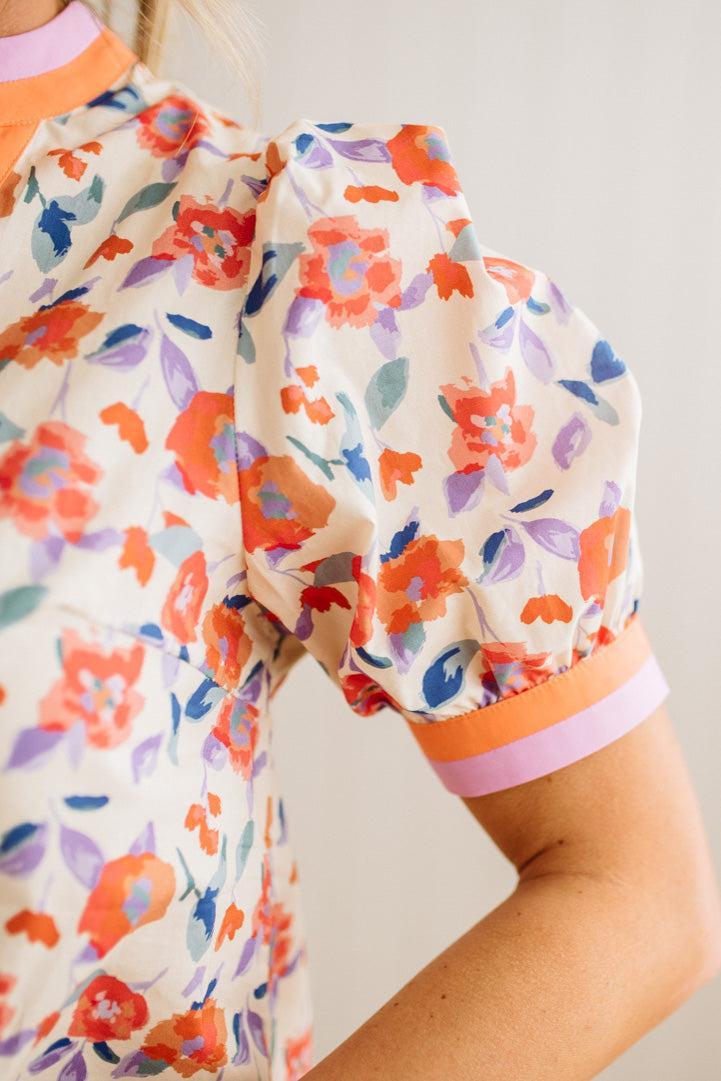 Close-up of a floral-patterned outfit with orange and pink accents on a plain background