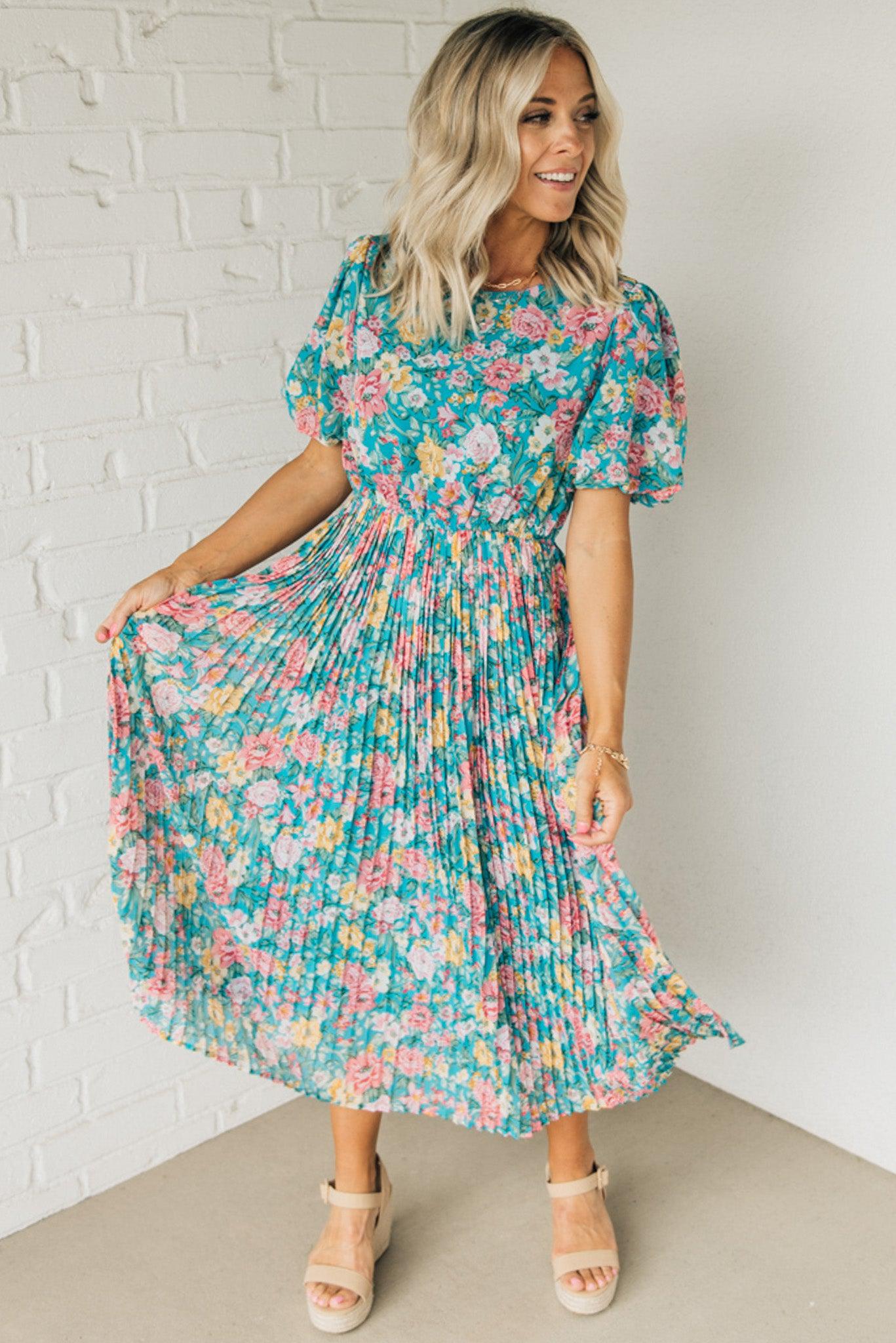 Women wearing a floral midi dress with short puff sleeves and a pleated skirt.