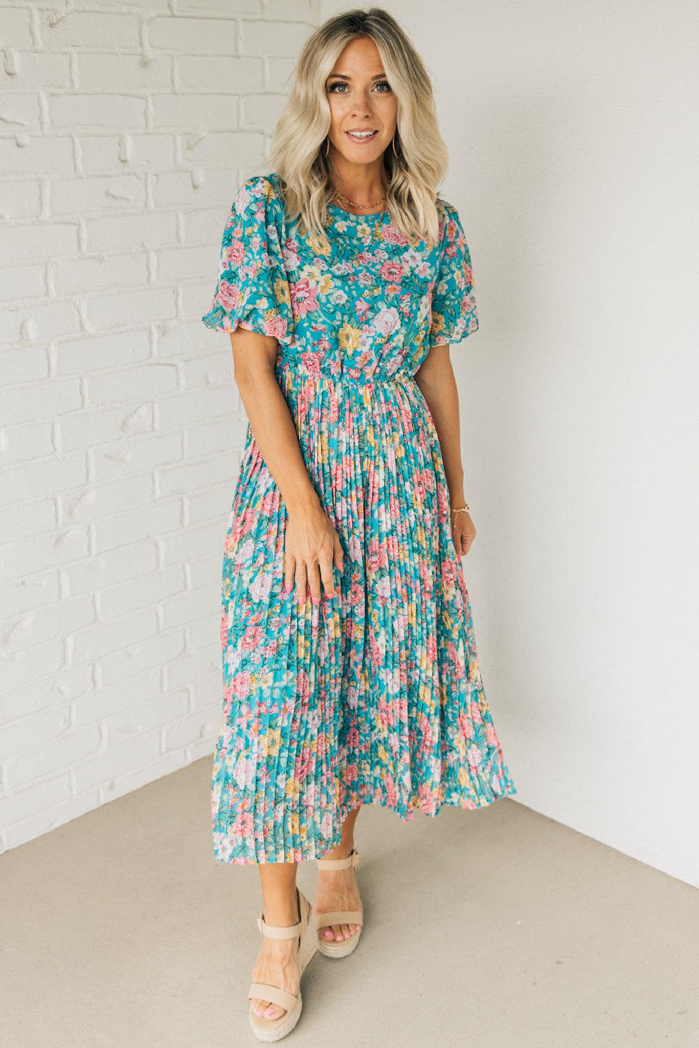 Women wearing a floral midi dress with short puff sleeves and a pleated skirt.