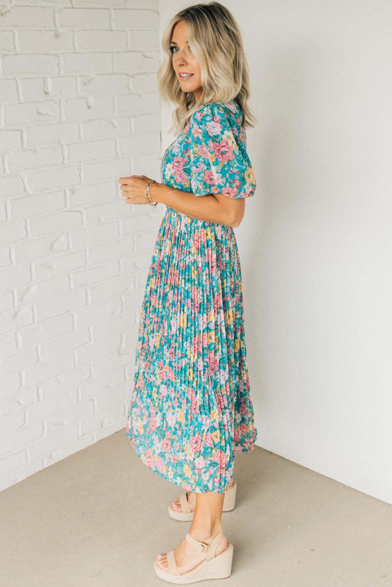 Women wearing a floral midi dress with short puff sleeves and a pleated skirt.