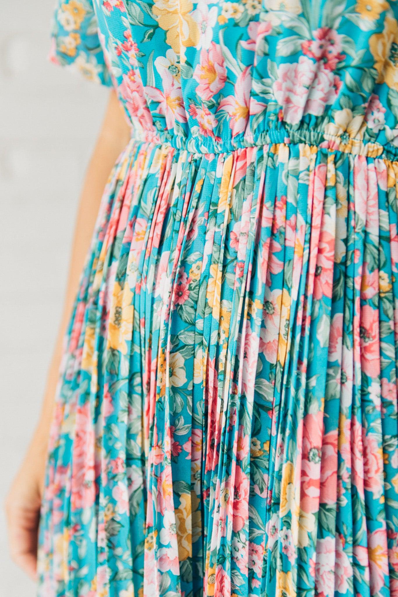 Women wearing a floral midi dress with short puff sleeves and a pleated skirt.