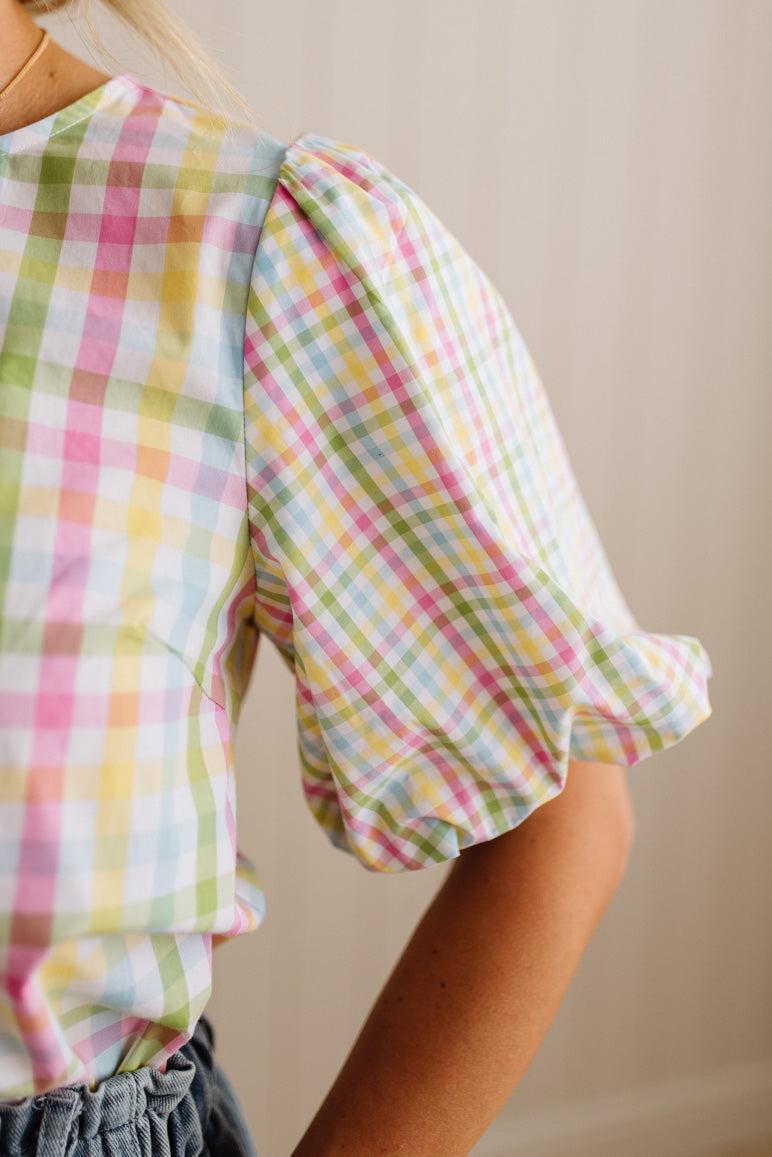 Person wearing a colorful plaid shirt with a neutral background
