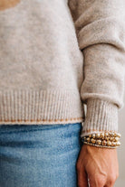 BLONDE WOMAN IN DARK JEANS WEARING A HORSE JACQUARD, STITCH TRIM ACCENT, LONG SLEEVE, CREW NECK PULLOVER SWEATER WITH A HORSE ON THE FRONT, AND WEARING A BIG BELT BUCKLE TOO.
