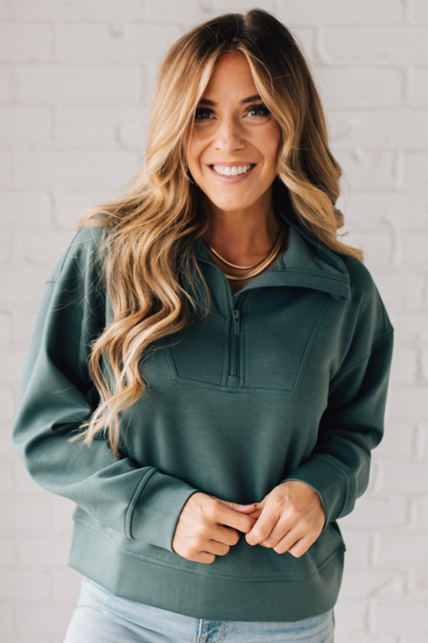 Women modeling a long sleeve, half zip solid colored scuba pullover in forest green