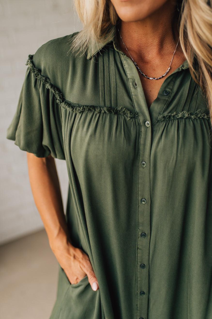 Woman wearing a green dress with ruffled sleeves against a neutral background