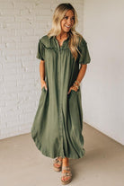 Woman wearing a green dress against a white brick wall.