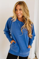 Woman wearing a blue sweatshirt with a plain background