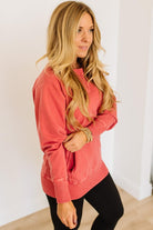 Woman wearing a pink sweatshirt and black pants against a white background