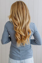 Person with long, wavy blonde hair wearing a blue top against a white background