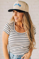 Blonde woman wearing a scoop neck, slim fit tee with vertical ribbed pattern, and horizontal printed stripes.