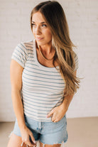 Blonde woman wearing a scoop neck, slim fit tee with vertical ribbed pattern, and horizontal printed stripes.