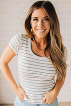 Blonde woman wearing a scoop neck, slim fit tee with vertical ribbed pattern, and horizontal printed stripes.