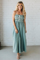 Woman wearing a light blue dress standing against a white brick wall.