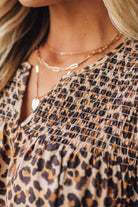 Blonde woman wearing an all over leopard print loose dress with side pockets, and layered ruffle sleeves trimmed with rickrack.
