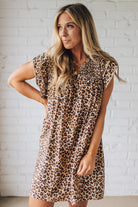 Blonde woman wearing an all over leopard print loose dress with side pockets, and layered ruffle sleeves trimmed with rickrack.