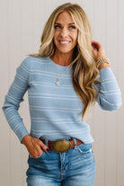 BLONDE WOMAN IN A STUDIO WEARING JEANS AND A BIG BELT WITH A BLUE RIBBED, LONG SLEEVE, CREW NECK, SUPER STRETCHY BASIC STRIPED INNER SWEATER.