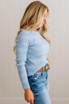 BLONDE WOMAN IN A STUDIO WEARING JEANS AND A BIG BELT WITH A BLUE RIBBED, LONG SLEEVE, CREW NECK, SUPER STRETCHY BASIC STRIPED INNER SWEATER.