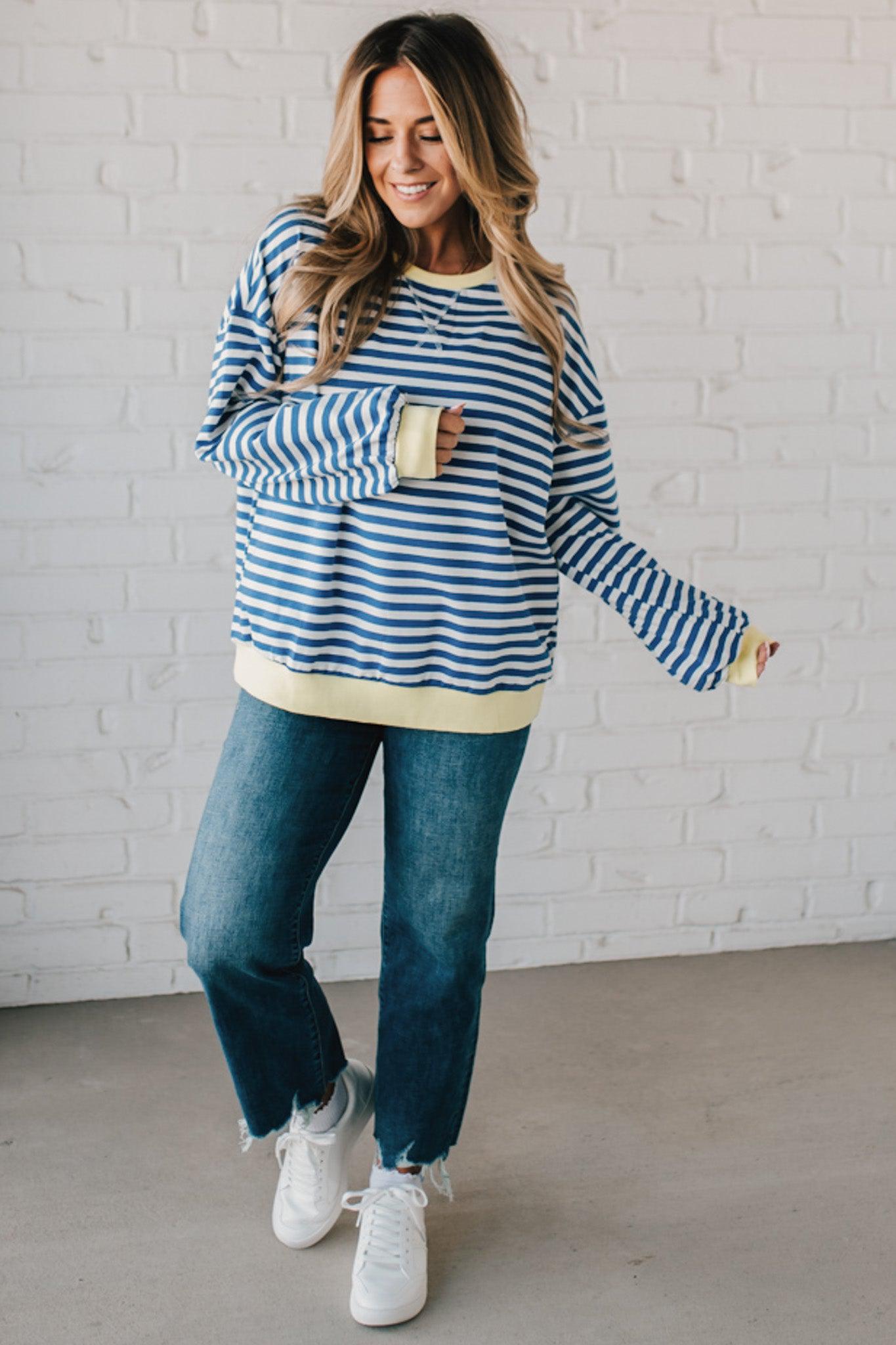 girl modeling a long sleeve oversized striped top with contrasting color on the sleeve cuff, neckline and hem