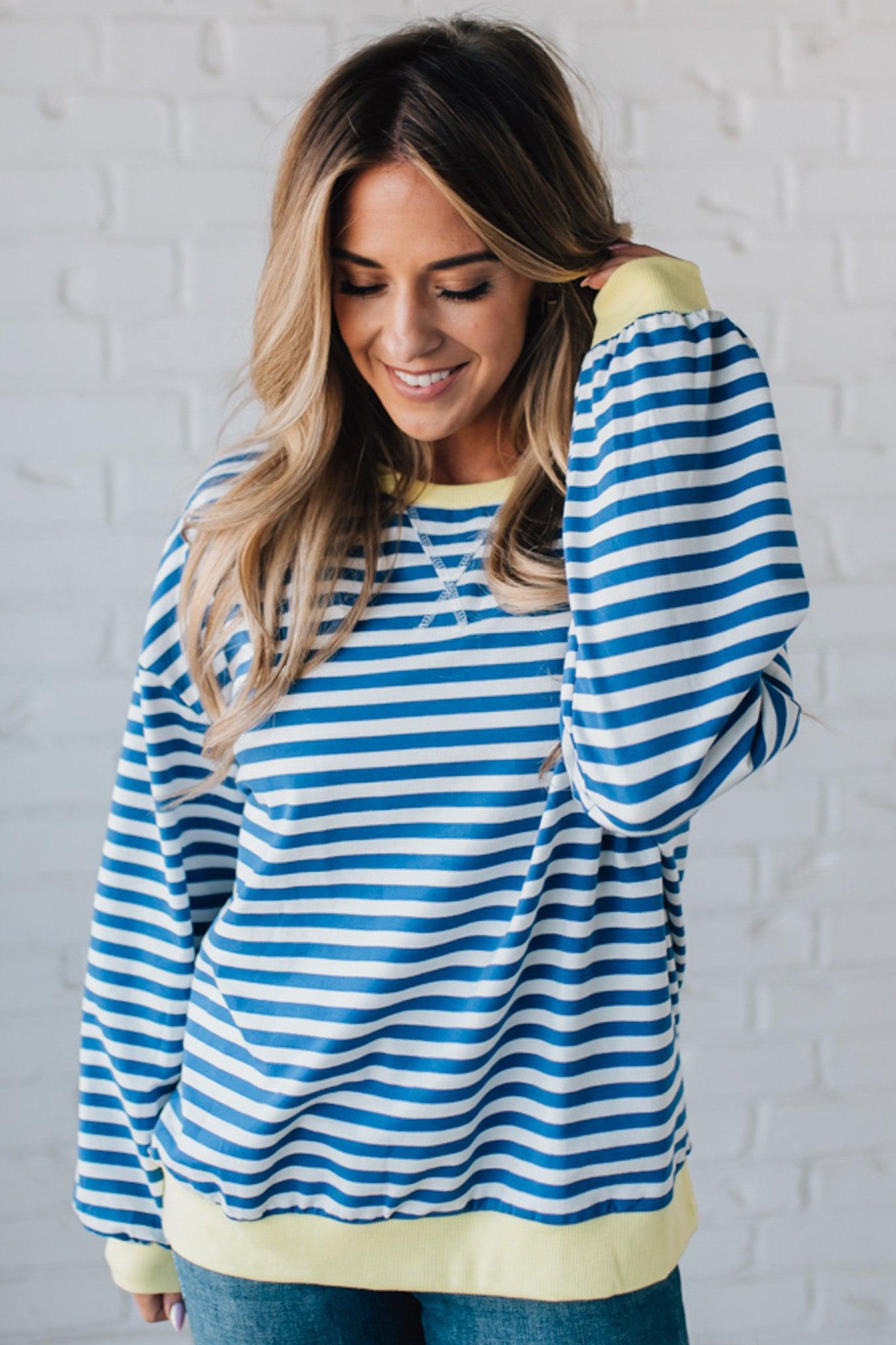 girl modeling a long sleeve oversized striped top with contrasting color on the sleeve cuff, neckline and hem